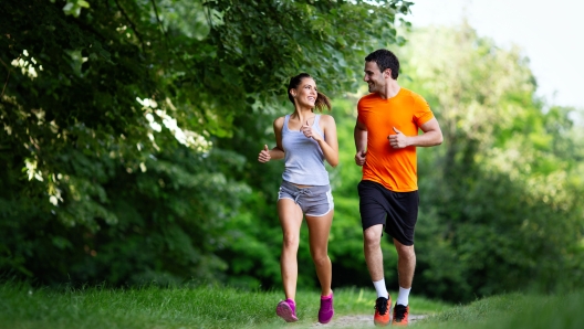 Portrait of happy young fit people running together ourdoors. Couple sport healthy lifetsyle concept