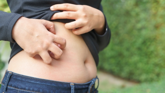 Chubby woman hand scratching her own belly fat.