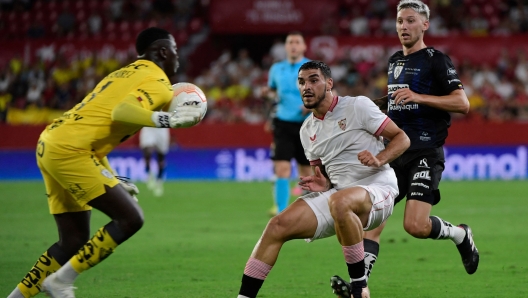 Sevilla's forward Carlos Isaac (C) challenges Independiente del Valle's goalkeeper Moises Ramirez (L) during the Club Challenge match between Sevilla FC and Independiente del Valle in Seville on July 19, 2023. The Club Challenge football match pits the UEFA Europa League winners Seville against CONMEBOL Recupa Sudamericana winners Ecuador's Independiente del Valle. (Photo by CRISTINA QUICLER / AFP)