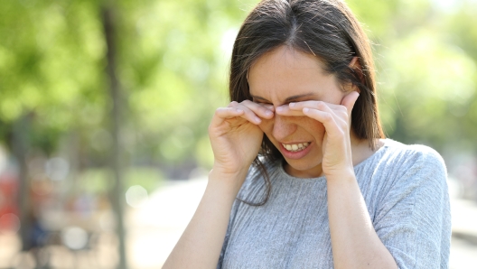 Disgusted woman rubbing her eyes in a park