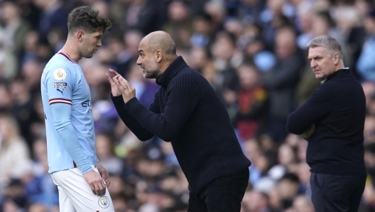 Manchester City's head coach Pep Guardiola, centre, talks to Manchester City's John Stones, left, as Leicester's head coach Dean Smith, right, looks on during the English Premier League soccer match between Manchester City and Leicester City at Etihad Stadium in Manchester, England, Saturday, April 15, 2023. (AP Photo/Dave Thompson)