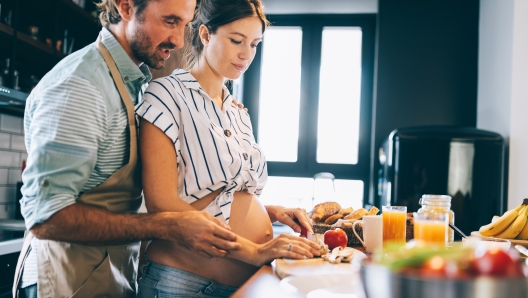 Beautiful young lovely couple is smiling while cooking together in kitchen at home