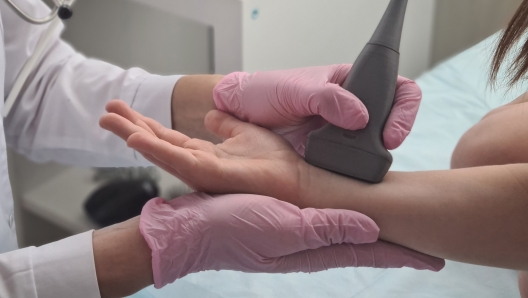 Doctor conducts ultrasound examination of patient child wrist in clinic. Ultrasound of wrist joints in medical center