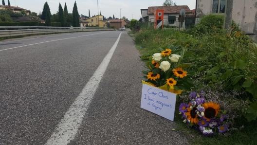 Fiori sul luogo in cui è stato investito, Negrar, 01 agosto 2023. Sognava di fare il calciatore da grande Chris Obeng Abom. La sua giovane vita, neppure 14 anni, è finita invece ieri notte a Negrar su una strada di provincia, falciato da un'auto pirata il cui conducente ha solo pensato a fuggire, senza voltarsi. Mentre questi si allontanava, Chris, di origini ghanesi è rimasto lì, sul bordo della Provinciale 12, senza marciapiede e male illuminata. Finchè un passante non si è accorto di lui, e ha dato l'allarme. Troppo tardi. ANSA/FILIPPO VENEZIA