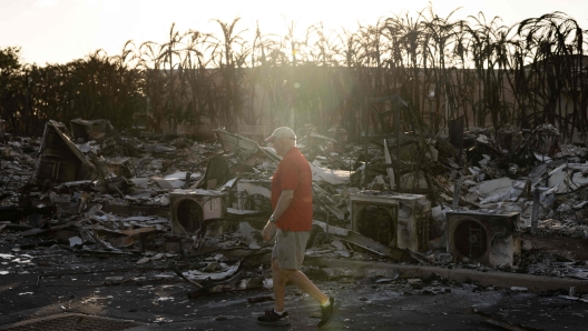 TOPSHOT - A resident looks around a charred apartment complex in the aftermath of a wildfire in Lahaina, western Maui, Hawaii on August 12, 2023. Hawaii's Attorney General, Anne Lopez, said August 11, she was opening a probe into the handling of devastating wildfires that killed at least 80 people in the state this week, as criticism grows of the official response. The announcement and increased death toll came as residents of Lahaina were allowed back into the town for the first time. (Photo by Yuki IWAMURA / AFP)