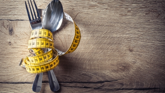 Spoon, fork and measuring tape on the kitchen table. The concept of a healthy diet.