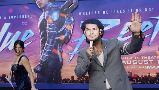 Angel Manuel Soto, right, director of "Blue Beetle," hides behind a cut-out of the film's star Xolo Mariduena as his wife, Carla Gonzalez, looks on at a screening of the film, Tuesday, Aug. 15, 2023, at the TCL Chinese Theatre in Los Angeles. Mariduena did not attend the premiere as per SAG-AFTRA guidelines during the current actors' strike. (AP Photo/Chris Pizzello)