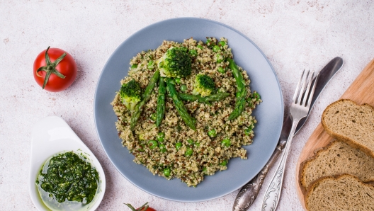 Vegetables with quinoa and green sauce in a dish on the table. Selective focus.