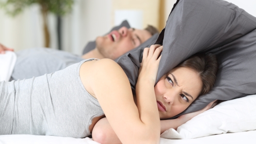 Man snoring and his wife covering ears