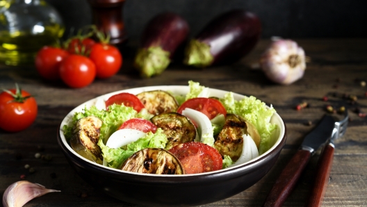 Vegetable salad with lettuce, tomatoes and grilled eggplants on the kitchen table.