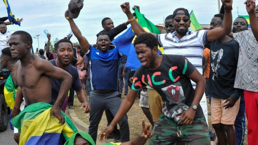 epa10828743 People wave Gabon national flags as they celebrate after a military coup, in the streets of Akanda, Gabon, 30 August 2023. Members of the Gabonese army on 30 August announced on national television that they were canceling the election results and putting an end to Gabonese President Ali Bongo's regime, who had been declared the winner.  EPA/STR