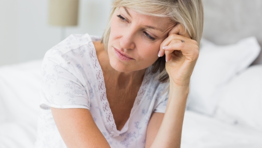 Closeup of a tensed mature woman sitting in bed at home