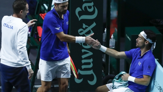 Italy's Simone Bolelli, center, touches hands with Fabio Fognini as Team Italy captain Filippo Volandri looks on during their match against Tommy Paul and Jack Sock of the USA in a Davis Cup quarter-final tennis match between Italy and USA in Malaga, Spain, Thursday, Nov. 24, 2022. (AP Photo/Joan Monfort)