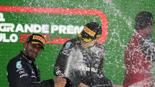 Second place finisher Mercedes driver Lewis Hamilton, of Britain, left, sprays champagne on race winner and teammate George Russell, of Britain, at the podium in the Brazilian Formula One Grand Prix at the Interlagos race track in Sao Paulo, Brazil, Sunday, Nov.13, 2022. (AP Photo/Andre Penner)