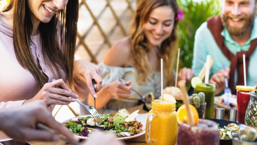 Happy friends lunching with healthy food in bar coffee brunch - Young people having fun eating meal and drinking fresh smoothies in restaurant - Health nutrition lifestyle concept