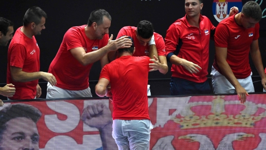 Serbia's Dusan Lajovic (C) is congratulated by teammates for beating South Korea's Seong-chan Hong during the group stage men's singles match between Serbia and South Korea of the Davis Cup tennis tournament at the Fuente San Luis Sports Hall in Valencia on September 12, 2023. (Photo by JOSE JORDAN / AFP)