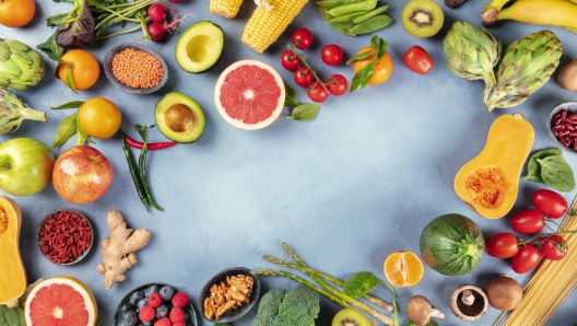 Vegan food, top-down shot of many different products, with vegetables and fruits, legumes, pasta and mushrooms, forming a frame with a place for text