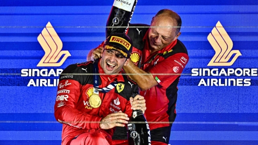 Ferrari's Spanish driver Carlos Sainz Jr (L) celebrates on the podium with Ferrari team principal Frederic Vasseur after winning the Singapore Formula One Grand Prix night race at the Marina Bay Street Circuit in Singapore on September 17, 2023. (Photo by Lillian SUWANRUMPHA / AFP)