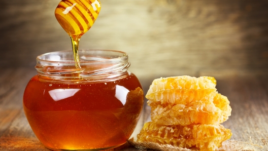 jar of honey with honeycomb on wooden table