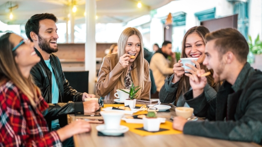 Friends group drinking cappuccino at coffee bar - People talking and having fun together at fancy cafeteria - Friendship concept with happy guys and girls at restaurant cafe - Warm bulb light filter