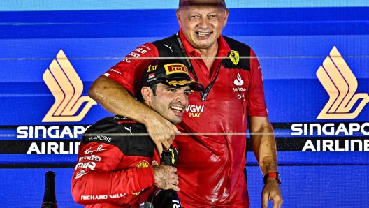 Ferrari's Spanish driver Carlos Sainz Jr (L) celebrates on the podium with Ferrari team principal Frederic Vasseur after winning the Singapore Formula One Grand Prix night race at the Marina Bay Street Circuit in Singapore on September 17, 2023. (Photo by Lillian SUWANRUMPHA / AFP)