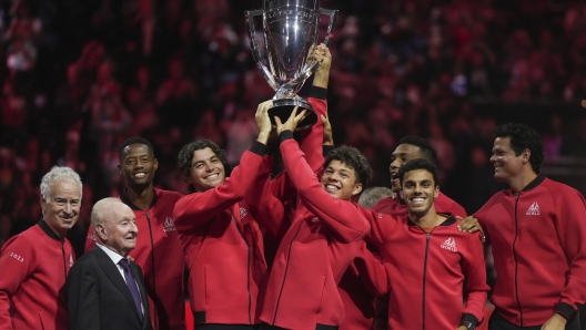 Team World's Taylor Fritz, fourth from left, and Ben Shelton, fifth from left, hoist the Laver Cup in front of teammates, John McEnroe, left, and Rod Laver, second from left, after Team World defeated Team Europe at the Laver Cup tennis tournament in Vancouver, British Columbia, Sunday, Sept. 24, 2023. (Darryl Dyck/The Canadian Press via AP)