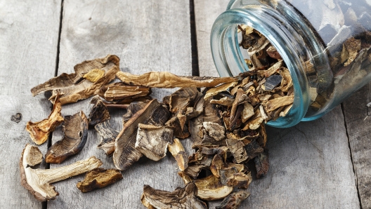 Dried mushrooms in a jar, sliced dried boletus on a wooden background