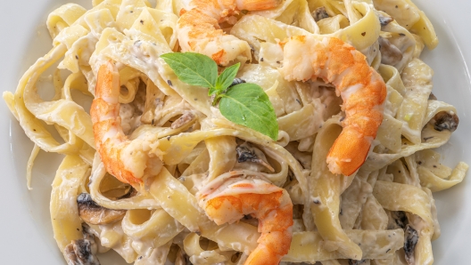 mushroom cream sauce spaghetti with shrimp on white dish put on the wooded table in italian restaurant