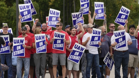 United Auto Workers members hold picket signs near a General Motors Assembly Plant in Delta Township, Mich., Friday, Sept. 29, 2023. The UAW union expanded its two-week strikes against Detroit automakers Friday, adding 7,000 workers at a Ford plant in Chicago and a General Motors assembly factory near Lansing, Michigan. (AP Photo/Paul Sancya)