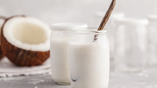 Homemade coconut yogurt in a glass jar on the table. Healthy vegan food concept.