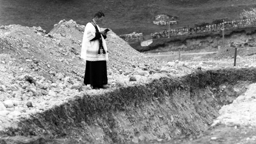 Un sacerdote prega tra le macerie a Longarone, uno dei paesi distrutti nella tragedia del Vajont. Il 9 ottobre 1963 alle 22.39, un'enorme frana di roccia di circa due chilometri quadrati di superficie e 260 milioni di metri cubi di volume, si stacca dalle pendici del Monte Toc, dietro la diga del Vajont, tra il Friuli e il Veneto: 1910 i morti, sette i paesi cancellati dalla tragedia. ANSA/ OLDPIX