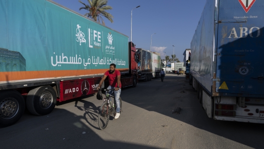 NORTH SINAI, EGYPT - OCTOBER 16: A person cycles past aid convoy trucks loaded with supplies on October 16, 2023 in North Sinai, Egypt. The aid convoy, organized by a group of Egyptian NGOs, set off today from Cairo for the Gaza-Egypt border crossing at Rafah. On October 7th, the Palestinian militant group Hamas launched a surprise attack on border communities in southern Israel, spurring the most violent flare-up of the Israel-Palestine conflict in decades. Israel launched a vast bombing campaign in retaliation and has warned of an imminent ground invasion. (Photo by Mahmoud Khaled/Getty Images)