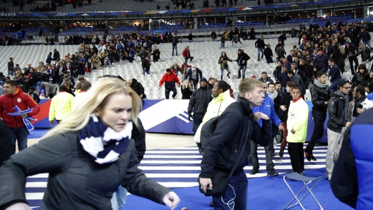 Spectators invade the pitch of the Stade de France stadium after the international friendly soccer match between France and Germany in Saint Denis, outside Paris, Friday, Nov. 13, 2015. Hundreds of people spilled onto the field of the Stade de France stadium after explosions were heard nearby during a friendly match between the French and German national soccer teams. French President Francois Hollande says he is closing the country's borders and declaring a state of emergency after several dozen people were killed in a series of unprecedented terrorist attacks.  (AP Photo/Christophe Ena)