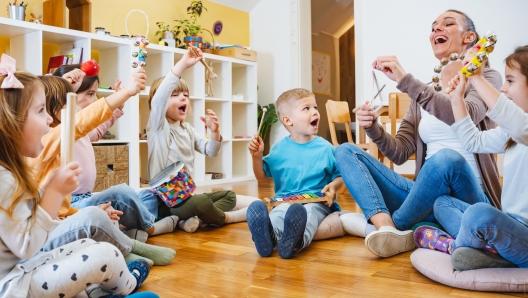 Teacher with children in a Kindergarten Classroom. Healthy learning environment. Kindergarten teacher, building relationships with the kids. Cheerful preschool children