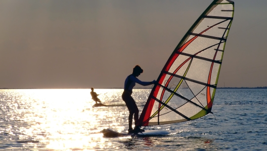 A women is learning windsurfing at the sunset