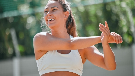 Fitness, sports and woman doing a stretching her arms before a workout or training outdoor in nature. Health, wellness and girl athlete doing a warm up exercise for her muscles, joints and body.