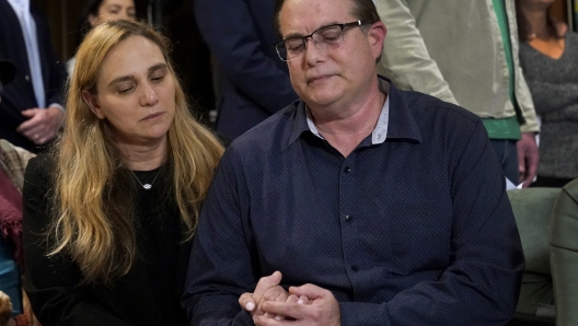 Sigal Zamir, left, and her husband Avi holds hands as they attend a prayer vigil for Judith Raanan and her daughter Natalie on Thursday, Oct. 12, 2023, in Evanston, Ill. Judith and Natalie are missing while visiting relatives in Nahal Oz for Simchat Torah, a festive Jewish holiday that marks the conclusion of the annual reading of the Torah. Sigal is the sister of Natalie's father Uri. (AP Photo/Charles Rex Arbogast)