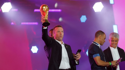 German former football player Lothar Matthaus poses on stage with the trophy during the FIFA Fan Festival opening day at Al Bidda park in Doha on November 19, 2022, ahead of the Qatar 2022 World Cup football tournament. (Photo by Odd ANDERSEN / AFP)