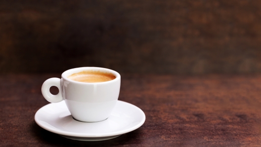 White cup of espresso coffee on background