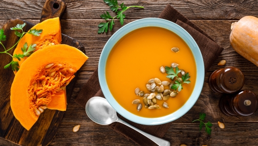 Pumpkin soup. Vegetarian soup with pumpkin seeds in bowl on wooden table, top view