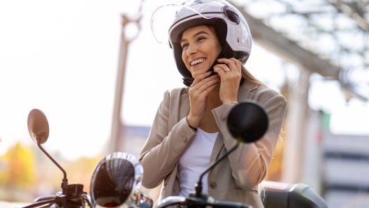 Woman on scooter tightens helmet