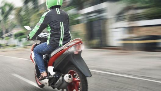 Rear view of motorcycle taxi ride with fast on the urban street