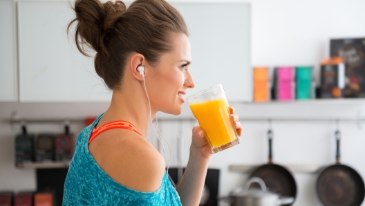 In her modern kitchen, a woman in profile is about to drink her freshly-made smoothie, which is packed with vitamins. A healthy lifestyle is so much fun.