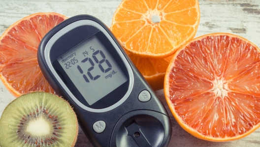 Glucometer with result of sugar level and fresh natural fruits. Diabetes and healthy lifestyle and nutrition