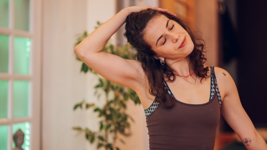 Close up cropped shot of a beautiful young girl with her eyes closed enjoying the morning yoga while pushing her head with her hand and stretching the neck muscles. Enjoying and breathing.Copy space.