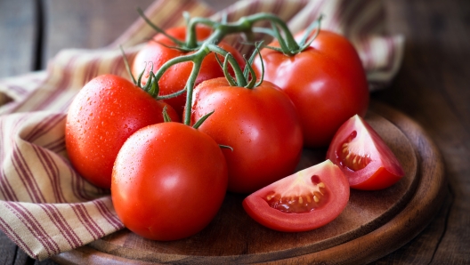 Fresh red ripe tomatoes on the vine on a dark rustic cutting board