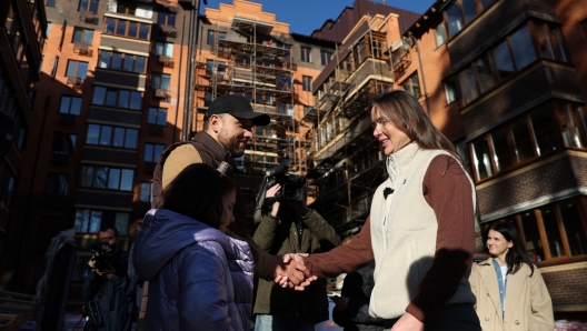 Ambassador of UNITED24 fundraising platform, Ukrainian professional tennis player Elina Svitolina (R) talks to local resident Anatolii (44) and his daughter Eva (9) during a visit to the reconstruction site of a building, which was damaged in last year's attacks in Irpin, outside Kyiv on November 7, 2023, amid the Russian invasion of Ukraine. (Photo by Anatolii Stepanov / AFP)