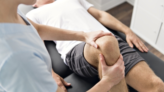 A Patient at the physiotherapy doing physical exercises with his therapist