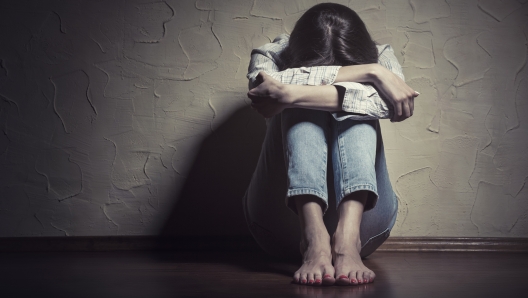 Young sad woman sitting alone on the floor in an empty room