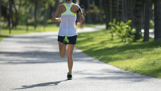 sporty fitness woman running at sunny park